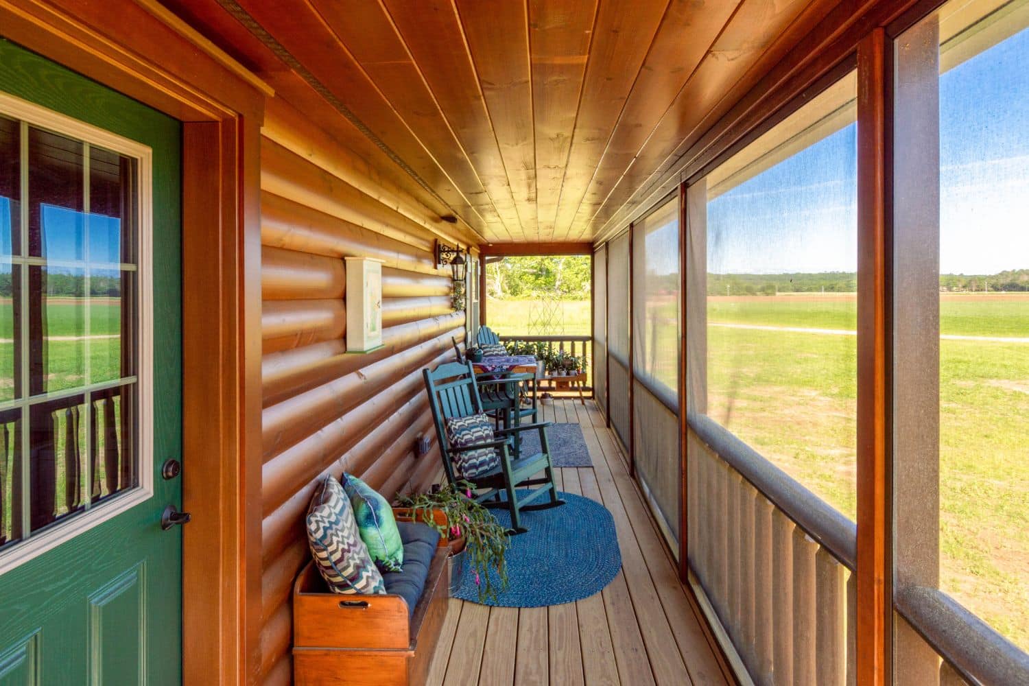 Inside a screened in log cabin front porch with view of seating