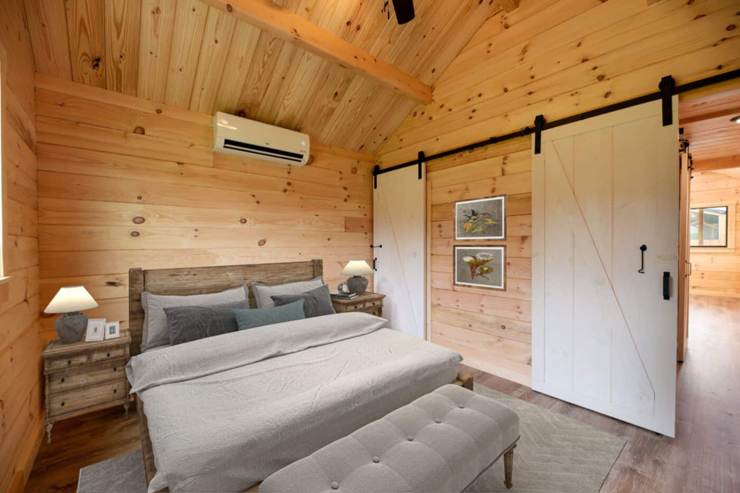 Tiny home bedroom in Kansas with bed, two night stands, wooden walls, and sliding barn doors.