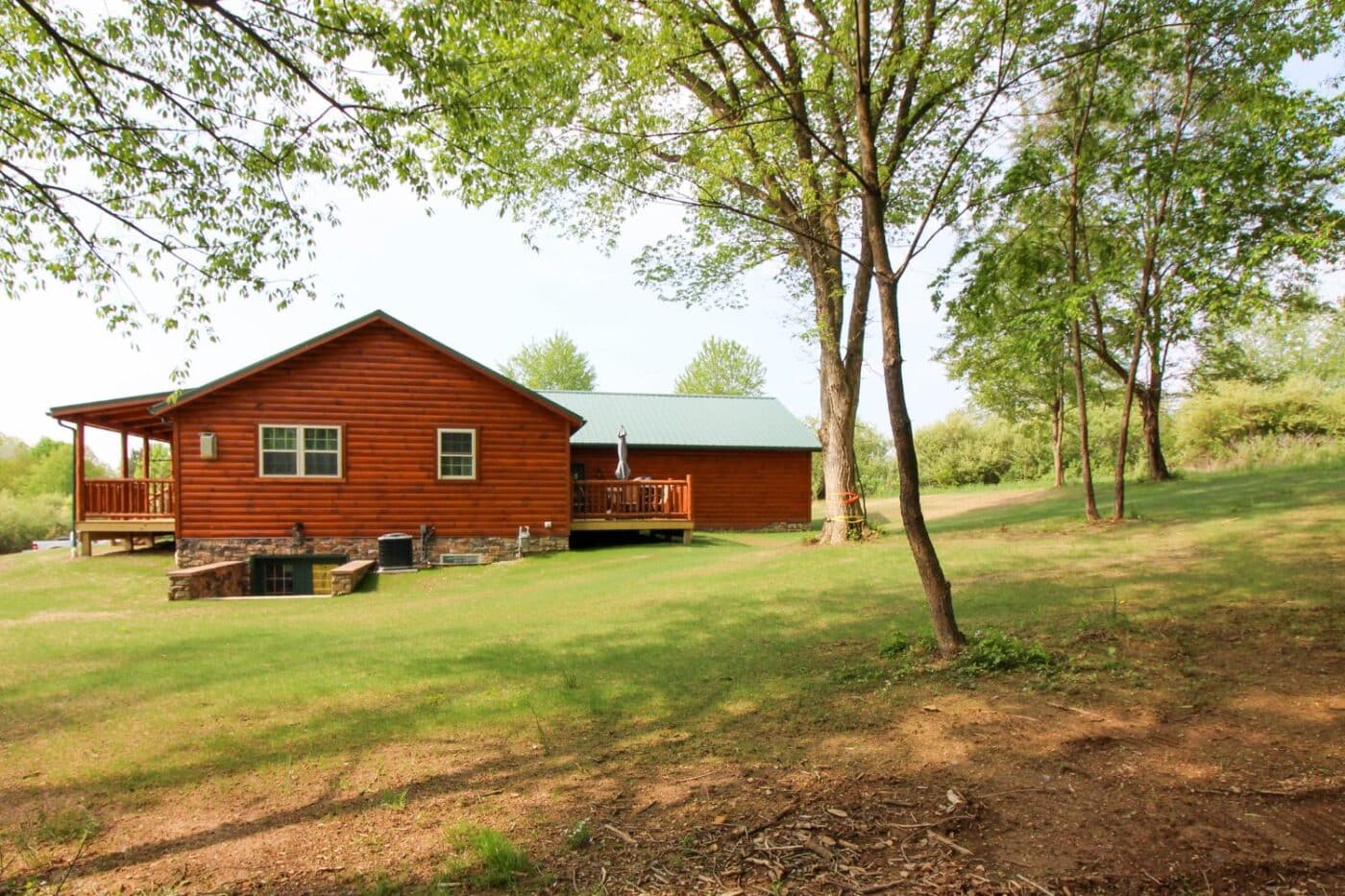 Log cabin at distance with view of land surrounding cabin and cabins porch and deck