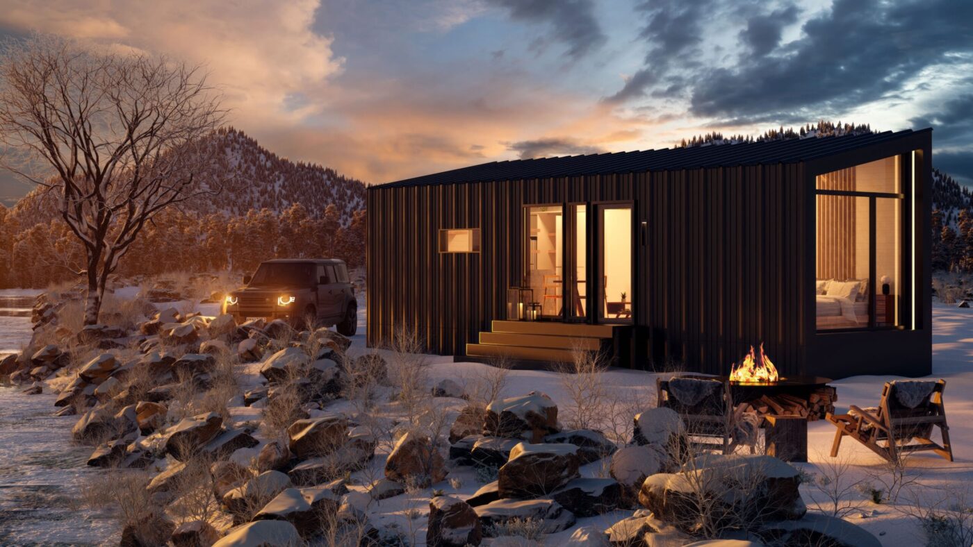 Modern black park model tiny home with large windows, shown at dusk in a snowy mountain setting with firepit and outdoor seating.