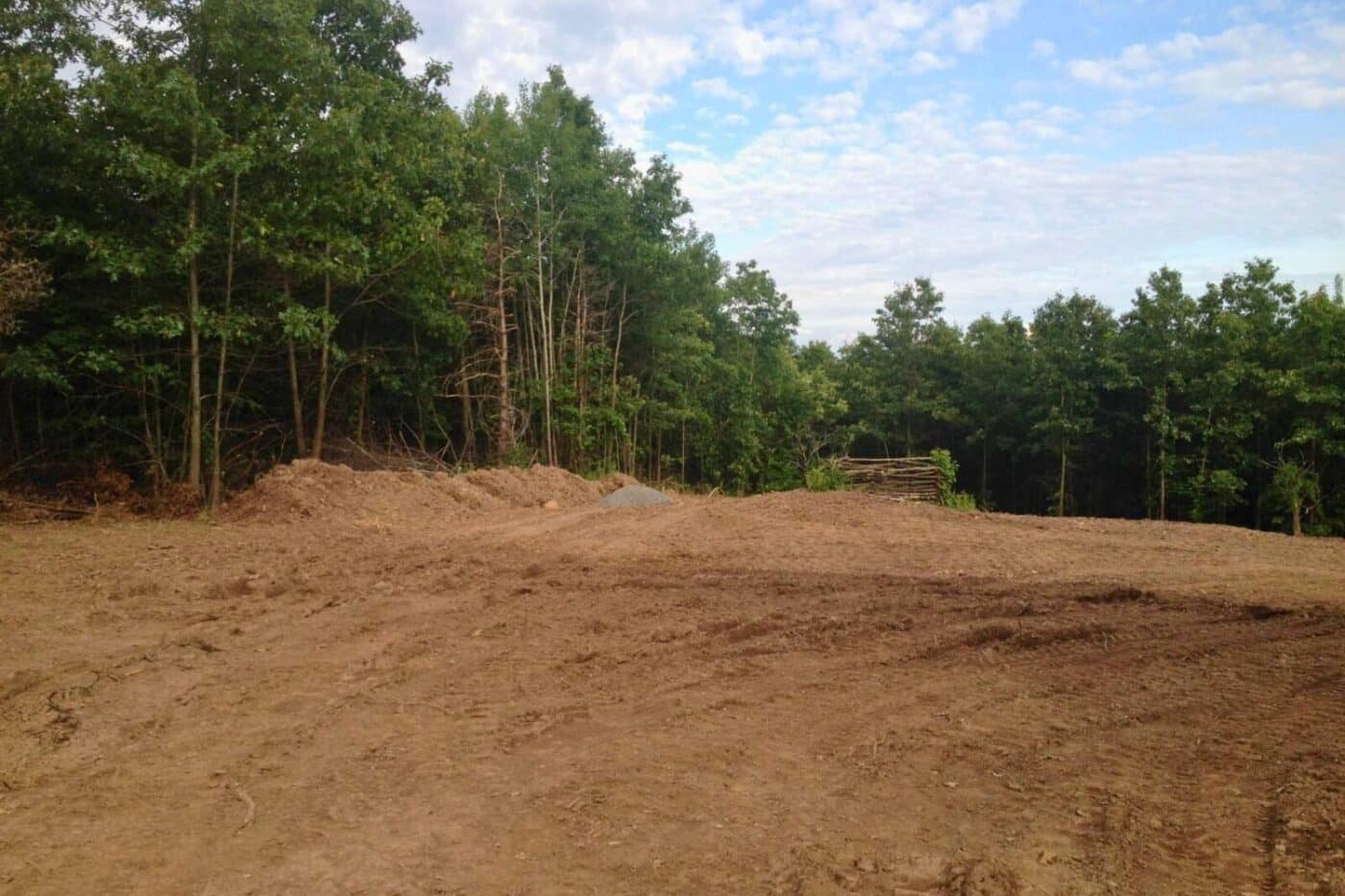 site cleared and prepped for log cabin foundation with trees on side and background