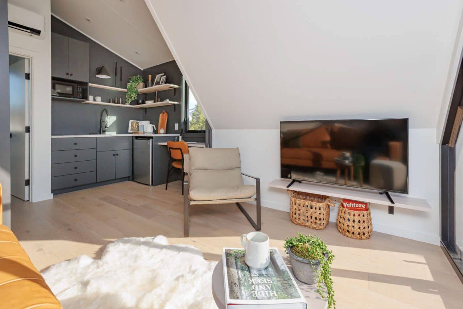 Tiny Home in Kansas, view of kitchen from living rooms, TV, chair, Yahtzee and fridge all visible
