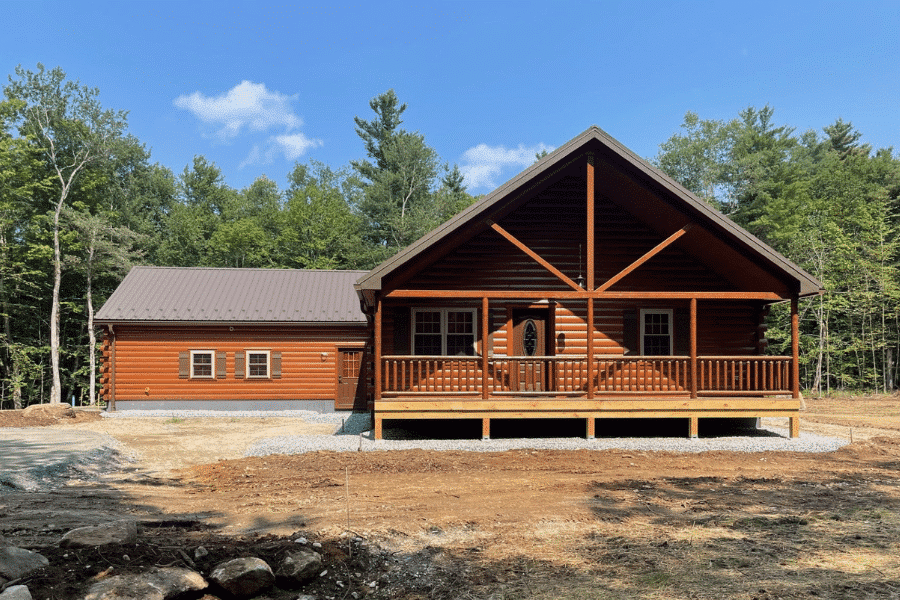 Settler log cabin with covered porch and wooded backdrop in New York.