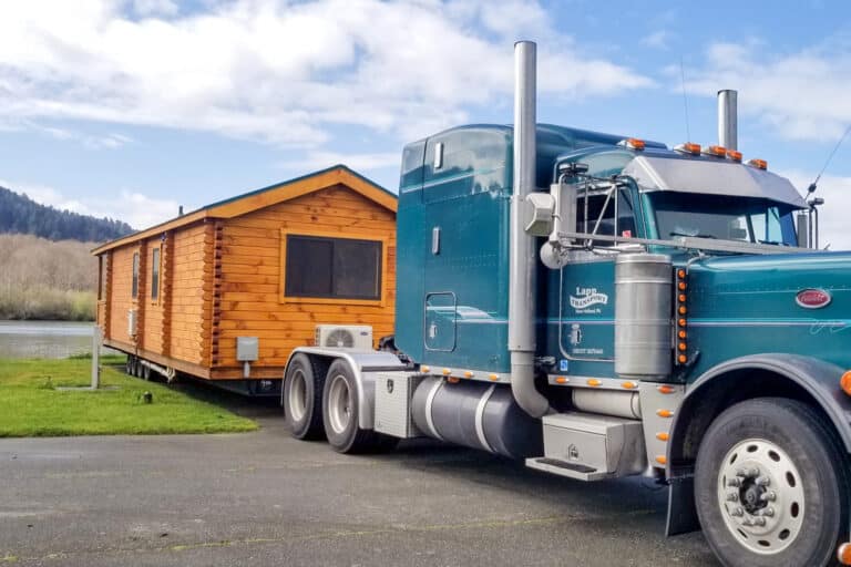 a semi packing a log Park Model home into position during delivery