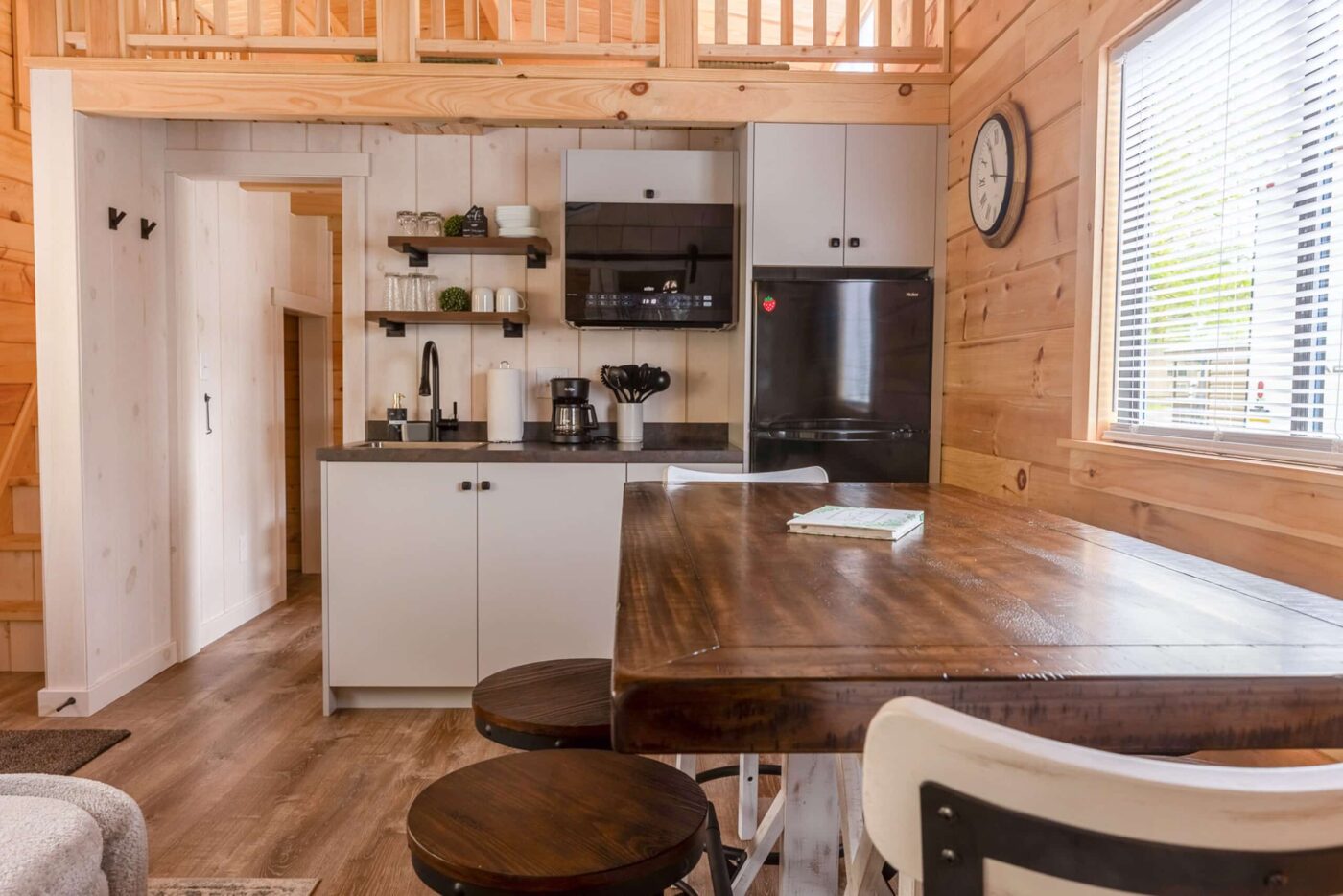 Rustic kitchen interior with wood finishes, dining table, and loft above.