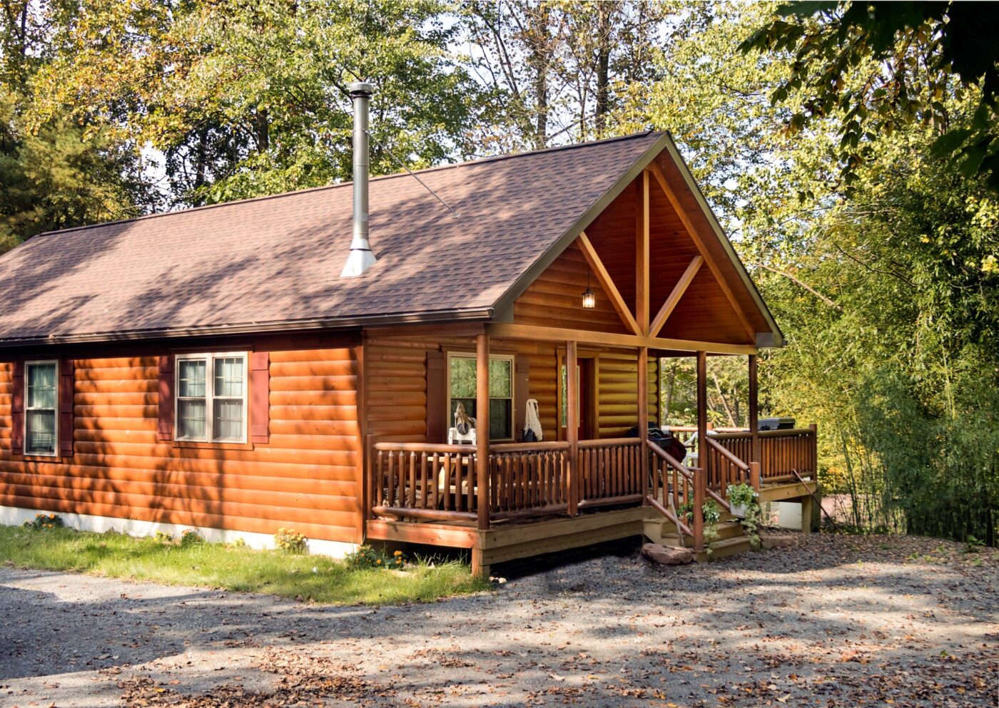 Settler log cabin with front porch, red shutters, and wooded backdrop in Virginia.