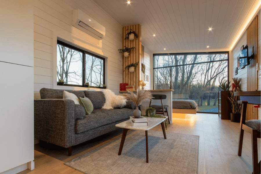 Bright living area inside Luna park model tiny home with large windows and modern furnishings.