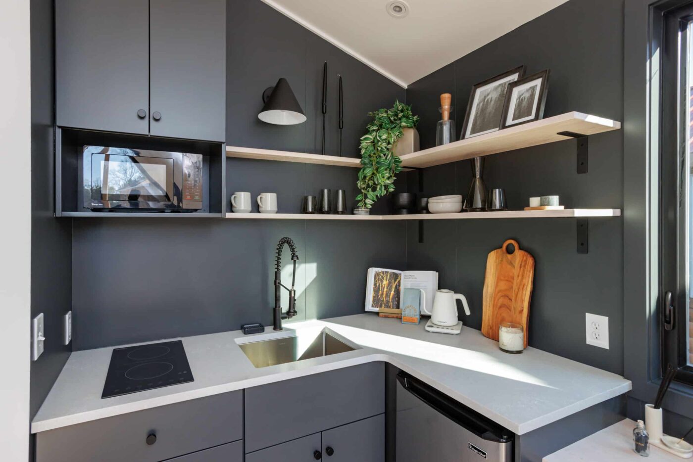 Compact kitchen with dark cabinetry, open shelving, and modern fixtures in a park model.