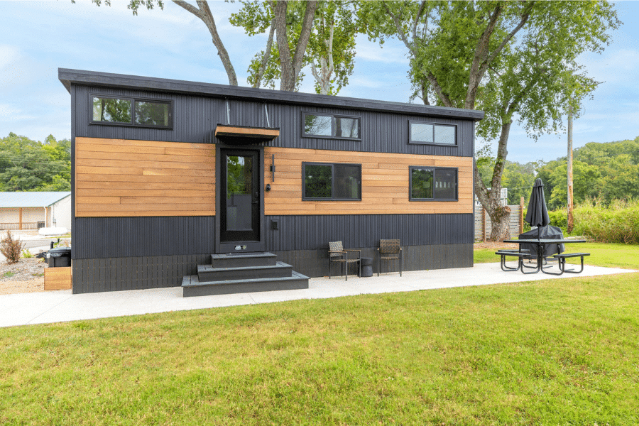 Modern Cascade park model tiny home with wood and metal siding in a grassy Rhode Island lot.