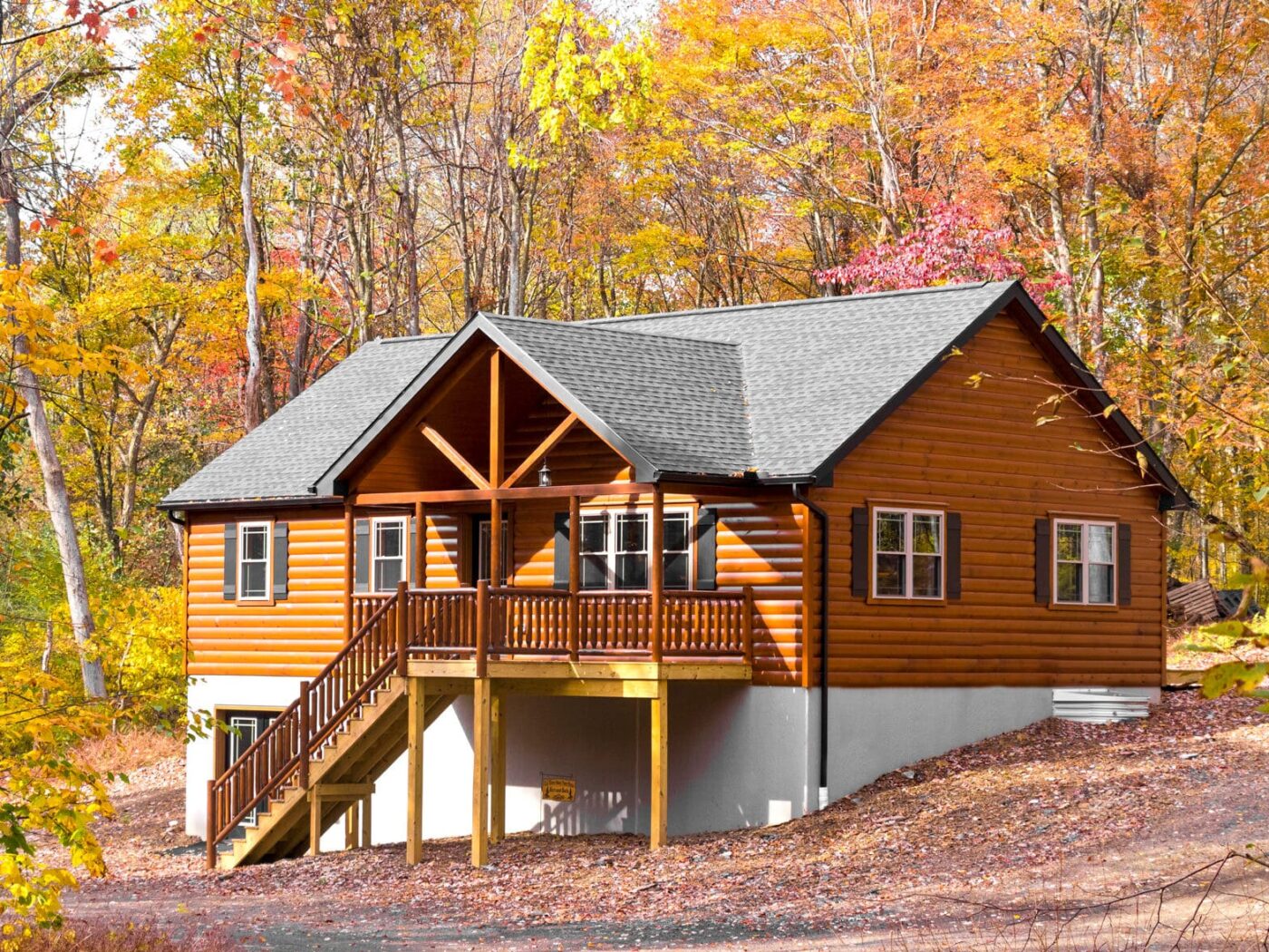 Pioneer log cabin in wooded New Hampshire setting with autumn leaves.